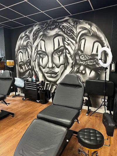 Schwarzes Wand-Mural mit drei Frauen-Gesichtern im Chicano-Stil über der Tätowierliege im 385-Ink-Studio.