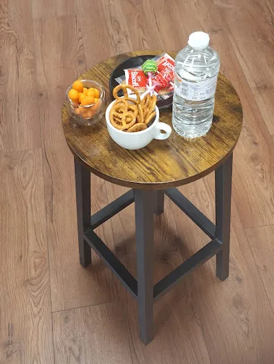Holzhocker mit einer Schale Brezeln, einer Schale Aprikosen, Schokolade und einer Wasserflasche — Snacks für Gäste im Studio.